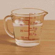 Measuring 50 ml of liquid in a glass jug next to ounce markings, showing an easy visual guide for converting milliliters to fluid ounces in the kitchen