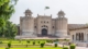 Lahore Fort main entrance with Pakistan flag, historic Mughal architecture, and landscaped gardens.