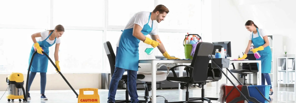 Professional cleaners providing Office Clean Out Services Kent WA in a modern, bright office space with cleaning supplies, vacuums, and "Wet Floor" signage.