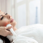 Woman receiving a professional skin tightening facial near Tysons Corner using a handheld device in a spa setting.
