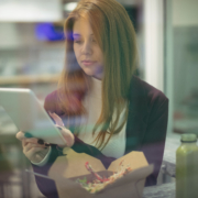 Woman using a digital tablet while eating salad, symbolizing how modern consumers engage with brands and build trust online.